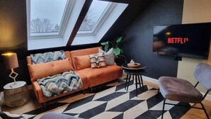 Een moderne woonkamer met een bank, een televisie, een bijzettafeltje en een stoel.