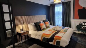 Een moderne hotelkamer met een groot bed, een nachtkastje, een lamp, een stoel en een schilderij aan de muur.