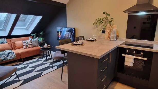 Een moderne keuken met een centraal eiland, een zithoek met een bank en een televisie.