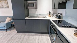 Een moderne keuken met een inbouwmagnetron, een spoelbak en een fornuis.