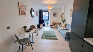 Een modern appartement met een eethoek, een bank, een televisie en een keuken.