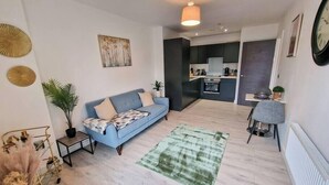 Een moderne woonkamer met een bank, een eethoek en een keuken op de achtergrond.