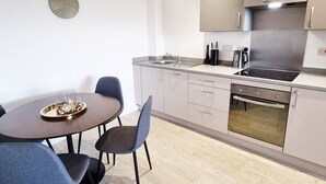 A modern kitchen with a dining table, chairs, a sink, a stove, and cabinets. - Media City Apartment (Greater Manchester)