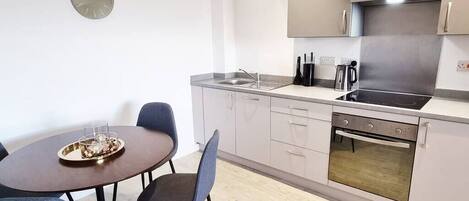 Una cocina moderna con una mesa de comedor, sillas, un fregadero, una estufa y alacenas.