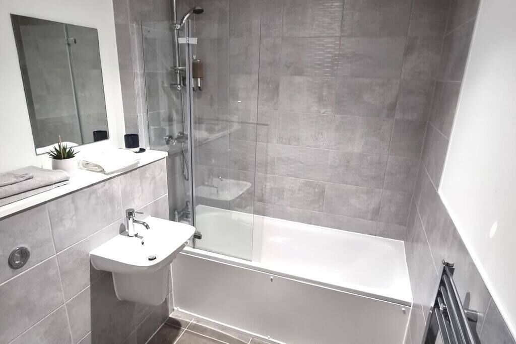 A modern bathroom with a glass-enclosed shower, a white sink, and a bathtub.