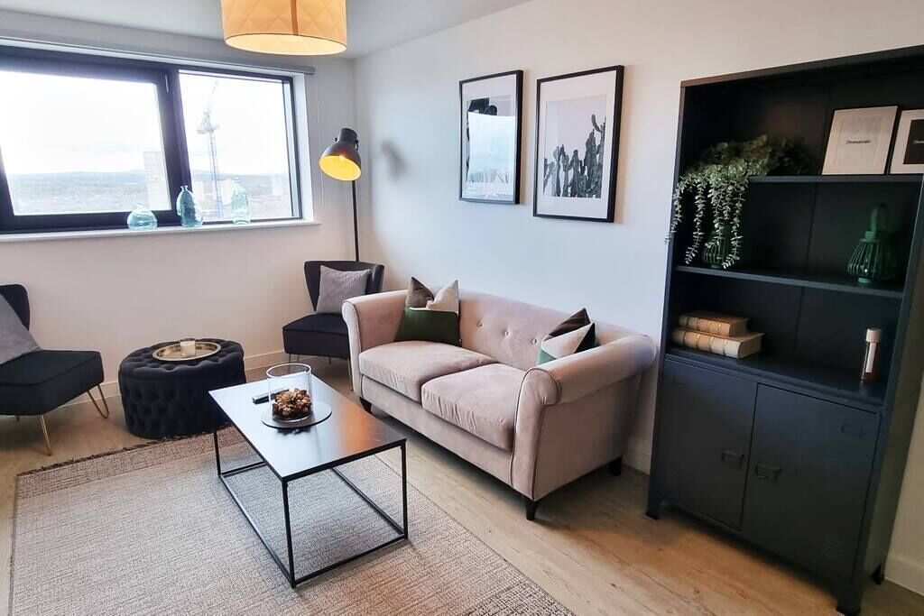 A modern living room with a sofa, a coffee table, a bookshelf, and a lamp.