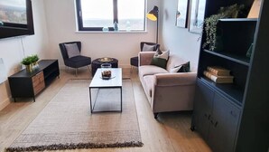A modern living room with a sofa, a coffee table, a TV, and a bookshelf. - Media City Apartment (Greater Manchester)