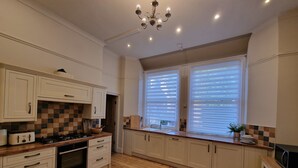 A kitchen with white cabinets, a wooden countertop, a stove, and a chandelier. - 6 Bed Mansion | Sleeps 20 | Free Parking (Ashton-under-Lyne)
