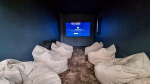 A home theater room with a flat-screen TV, bean bag seating, and a carpeted floor. - 6 Bed Mansion | Sleeps 20 | Free Parking (Ashton-under-Lyne)