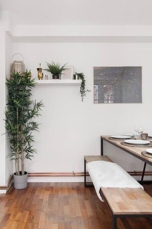 A room with a wooden bench, a potted plant, a shelf with decorative items, and a framed picture on the wall. - Beamed Northern Quarter Loft | 2 Bed | Sleeps 6 (Greater Manchester)