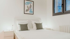 A bedroom with a bed, white nightstands, a framed picture, and a window. - Paillette (Centre-Ville) (Le Havre)