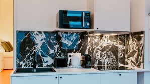 A modern kitchen with a white countertop, a black and white marble backsplash, and a white cabinet above the sink. - Paillette (Centre-Ville) (Le Havre)