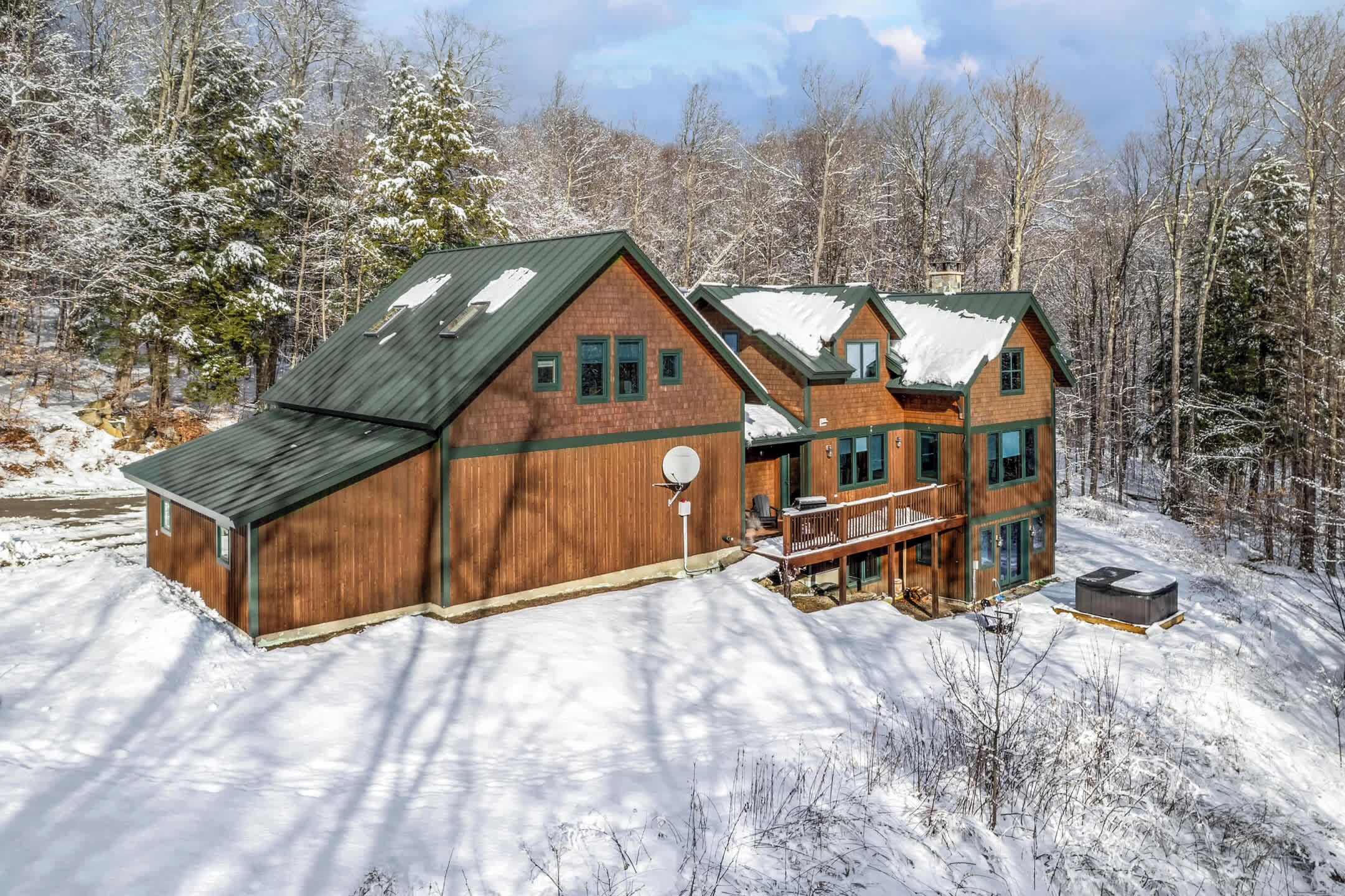 A large wooden cabin with a green roof, surrounded by snow-covered trees.