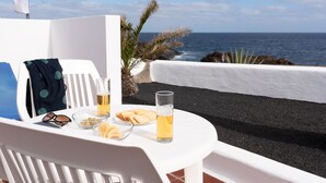 A white table with a glass of beer, snacks, and sunglasses on a balcony overlooking the ocean. - Delmar Natur - Cherne (Charco del Palo)