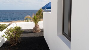 A narrow pathway leading to a balcony with a view of the sea, white walls, and a blue umbrella. - Delmar Natur - Cherne (Charco del Palo)