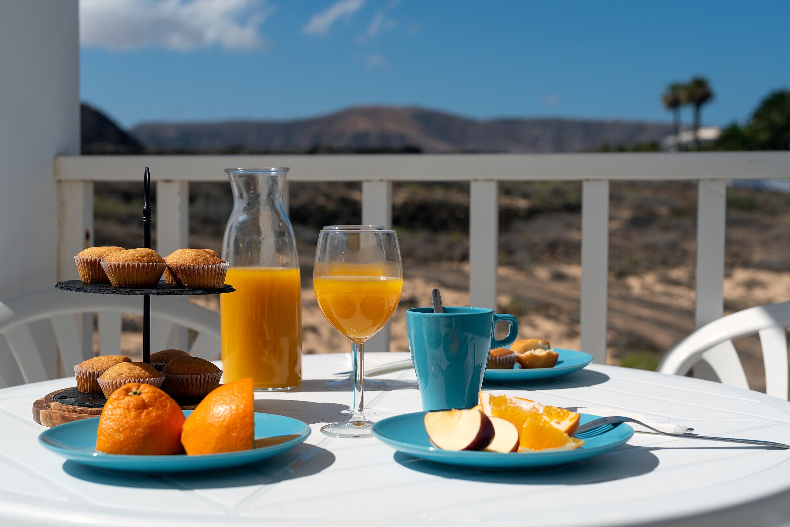 Un plateau de petit-déjeuner comprenant des muffins, du jus d’orange et un verre de jus d’orange, le tout disposé sur une table offrant une vue panoramique.