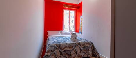 Une chambre avec un lit, une fenêtre donnant sur un beau paysage et un mur d’accent de couleur rouge.