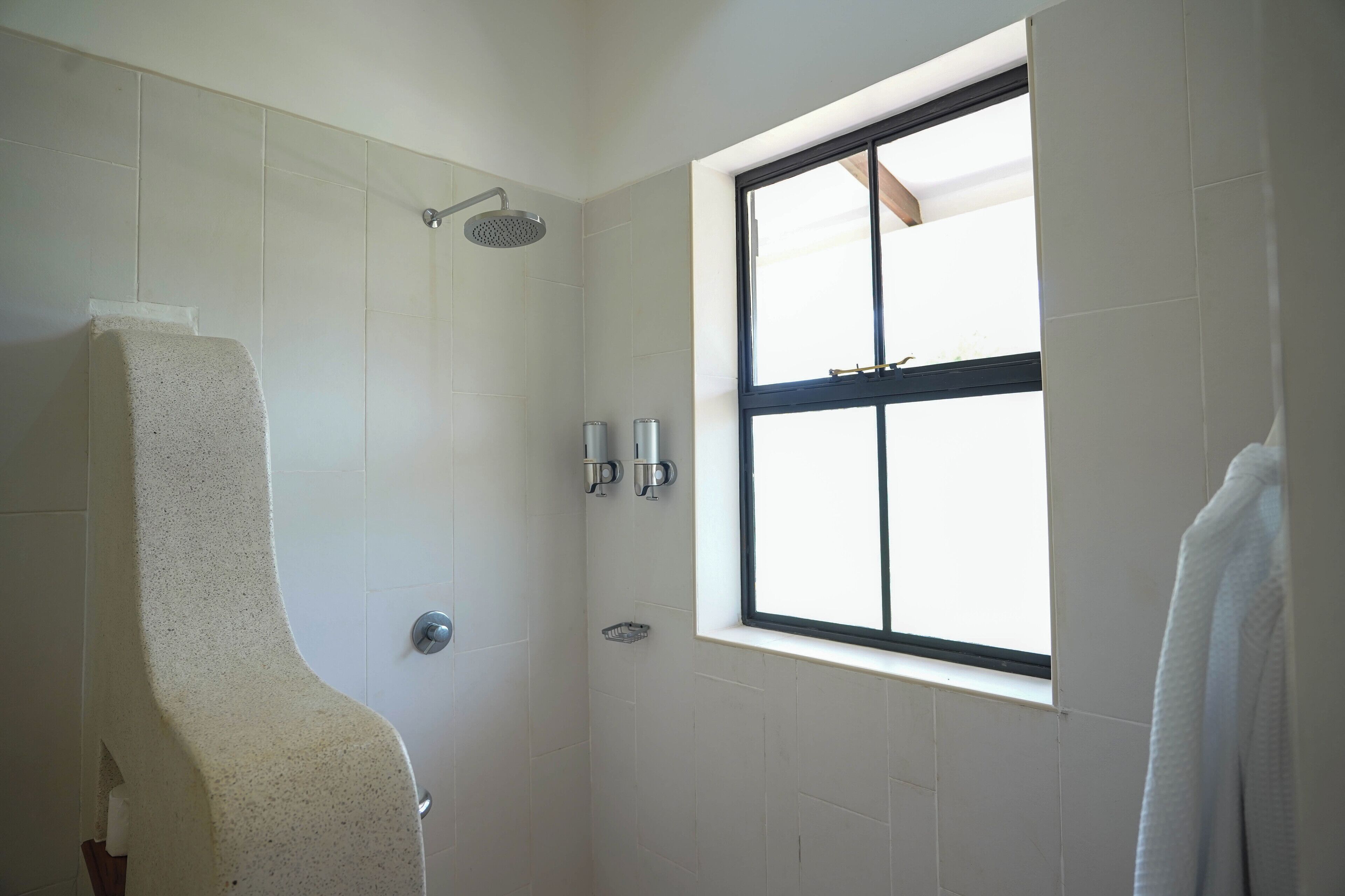 A bathroom with a shower, a window, and a towel rack.