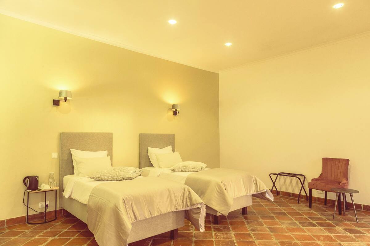 Una habitación de hotel con dos camas, una silla y una mesita.