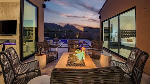 Une terrasse extérieure moderne, dotée d’un espace salon, d’un foyer et offrant une vue sur les montagnes.