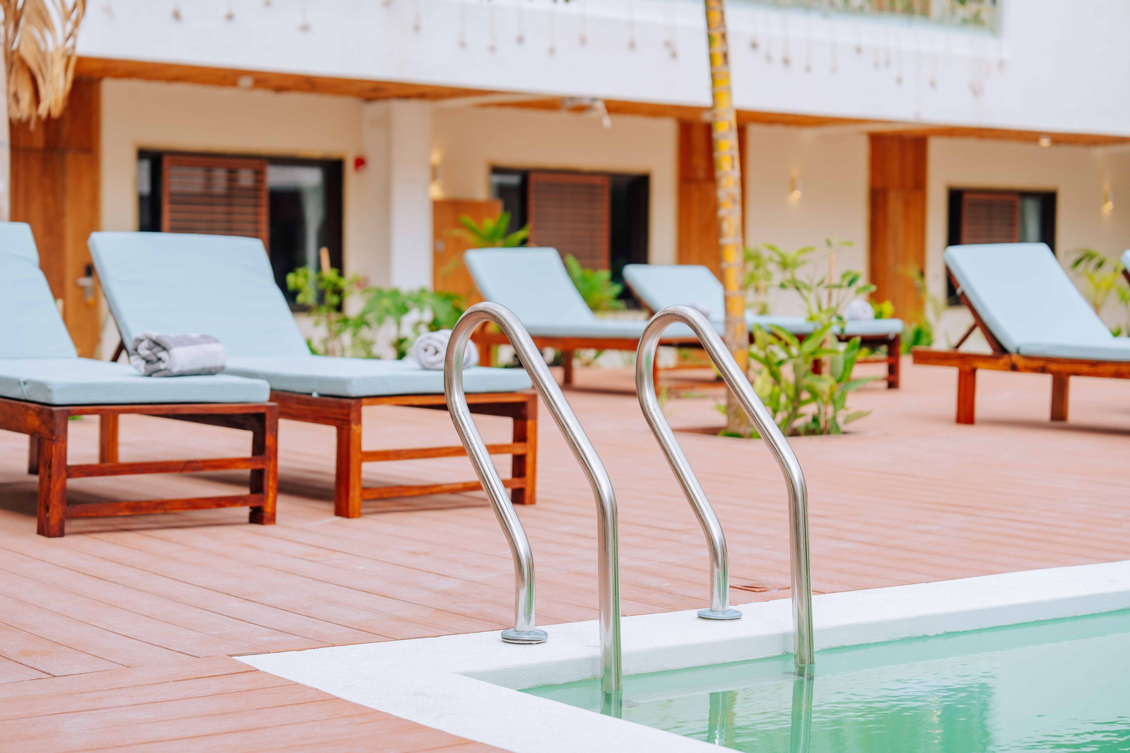 A poolside area with lounge chairs and metal pool ladders.