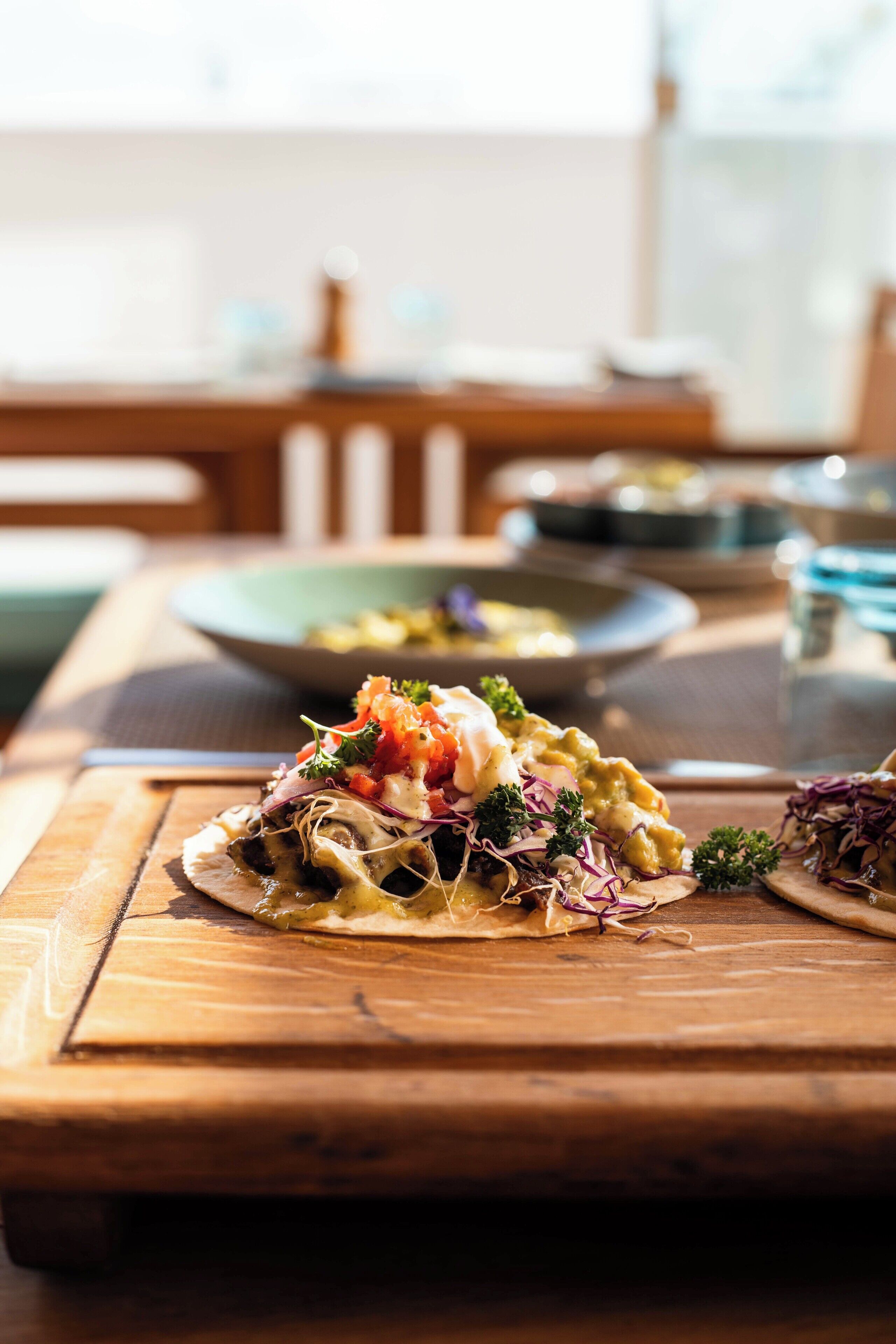 A wooden table with a plate of food, a bowl, and a glass of water.