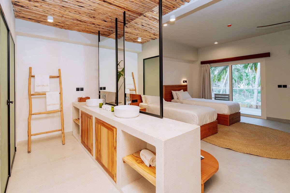 Ein modernes Schlafzimmer mit einem großen Bett, einem Nachttisch, einem Einbauschrank und einem Badezimmer mit Waschbecken und Spiegel.
