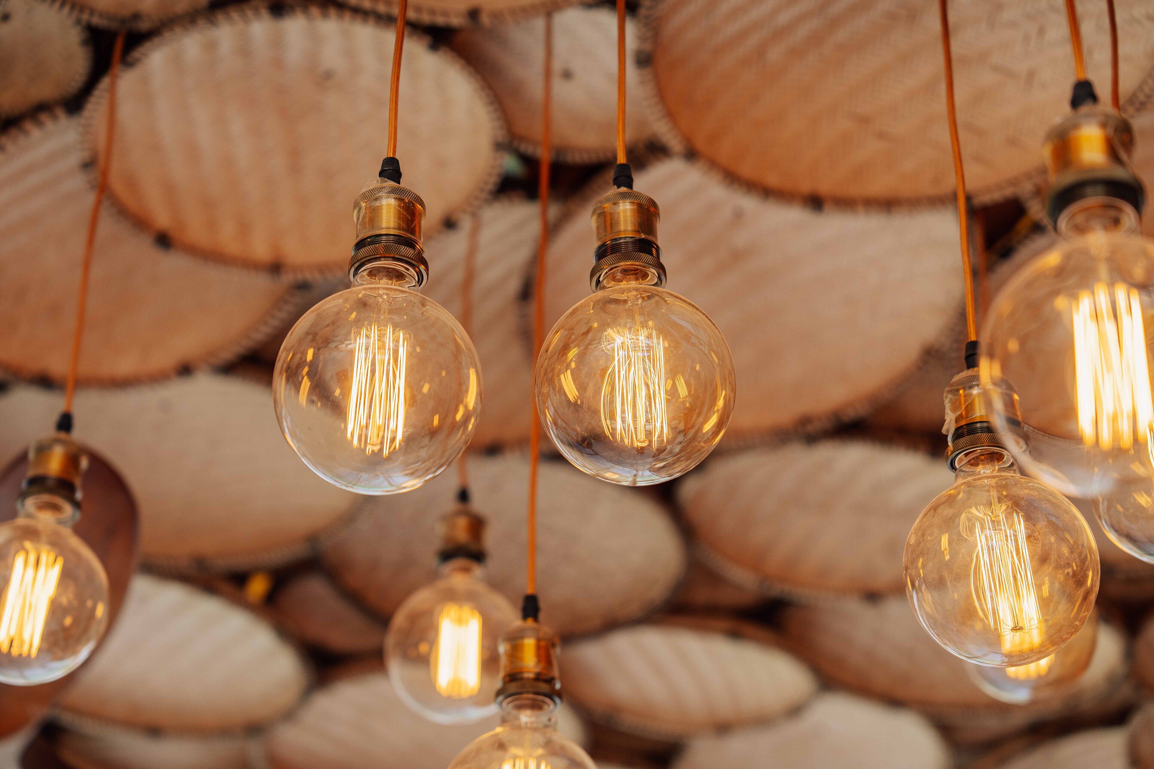 A wall of round, clear glass bulbs with visible filament filaments, suspended by thin wires.