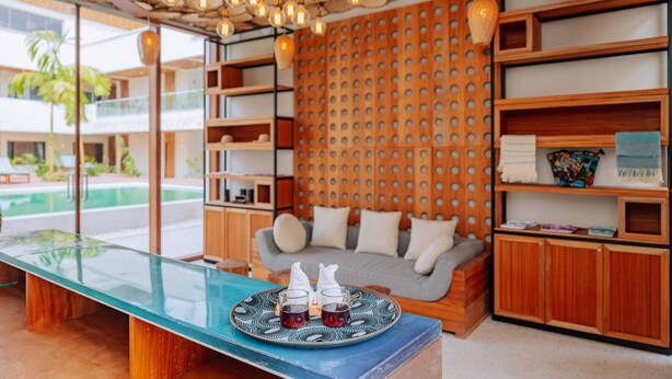 A modern interior with a glass table, wooden shelves, and a patterned wall. - Samawa Living (Paje)