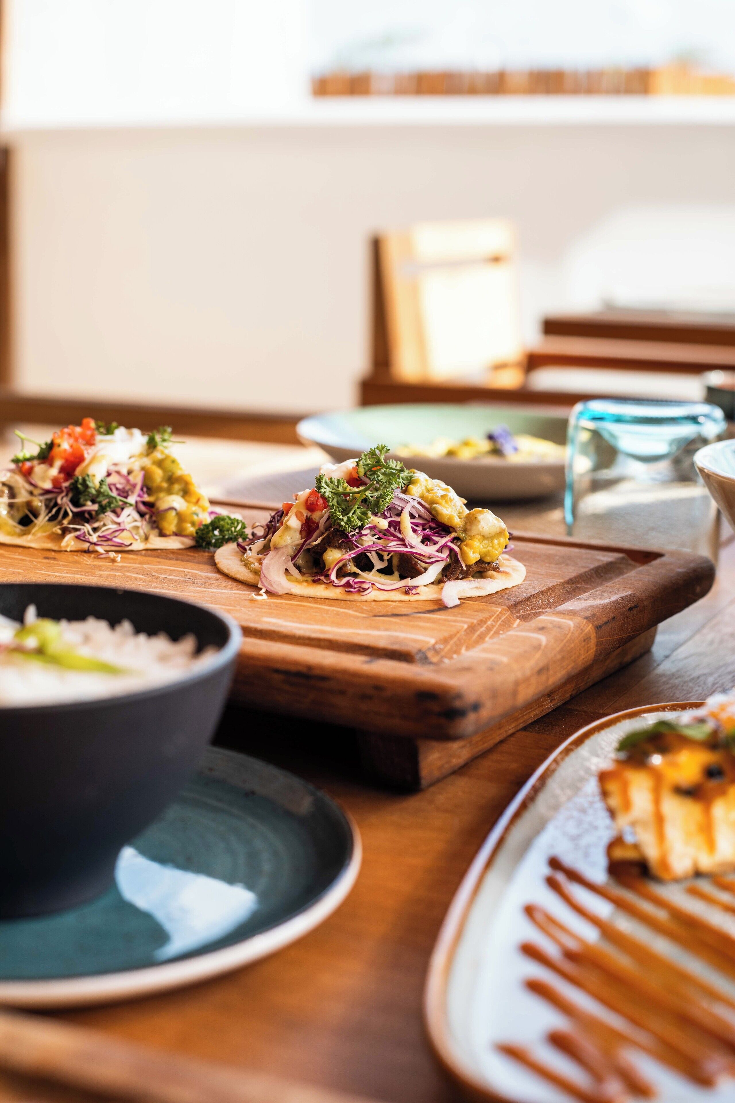 A dining table with various dishes, including tacos and a bowl of rice.