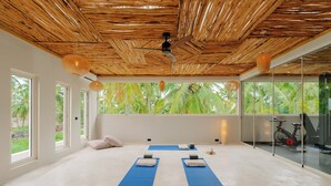 A spacious room with a bamboo ceiling, large windows, and exercise equipment. - Samawa Living (Paje)