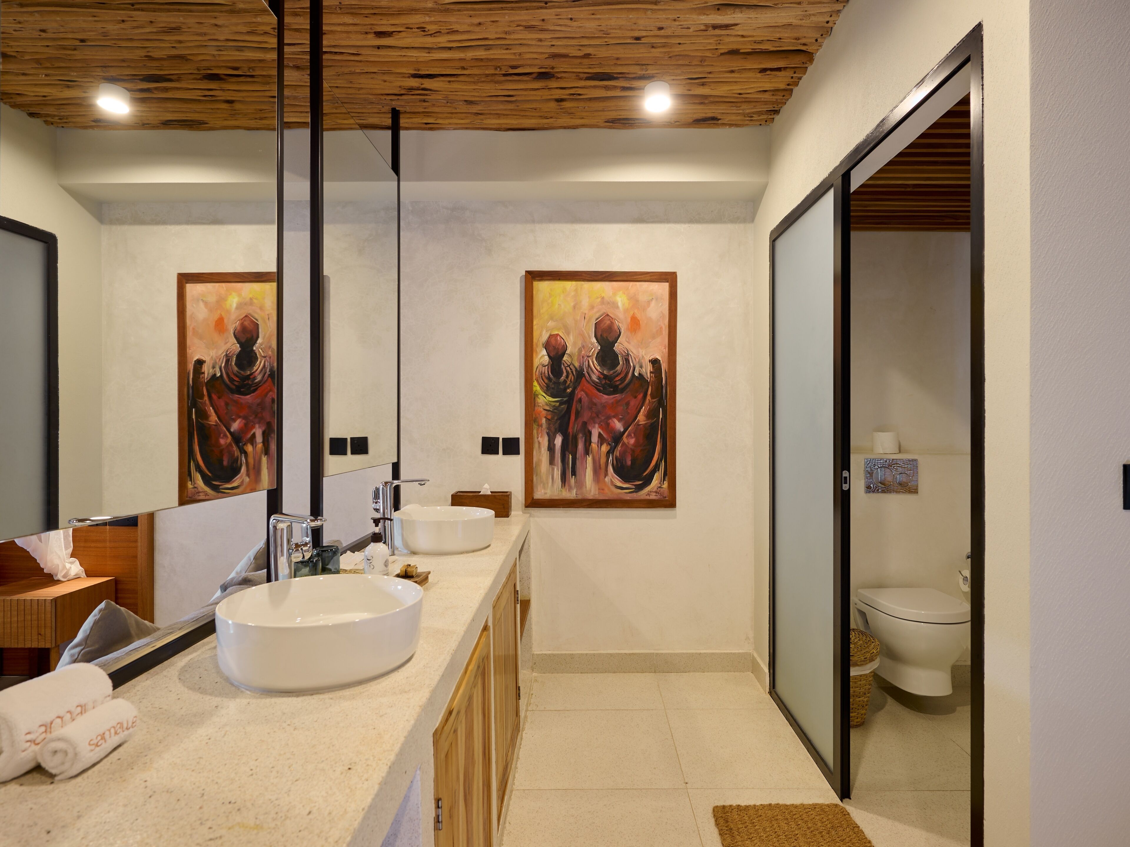 Un bagno moderno con uno specchio grande, due lavabi, mobili in legno e un quadro appeso al muro.