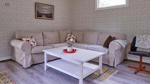 Un salon avec un canapé beige, une table basse blanche et un tapis à motifs.
