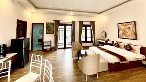 Habitación de hotel con cama, escritorio, silla, televisor y ventana con cortinas.