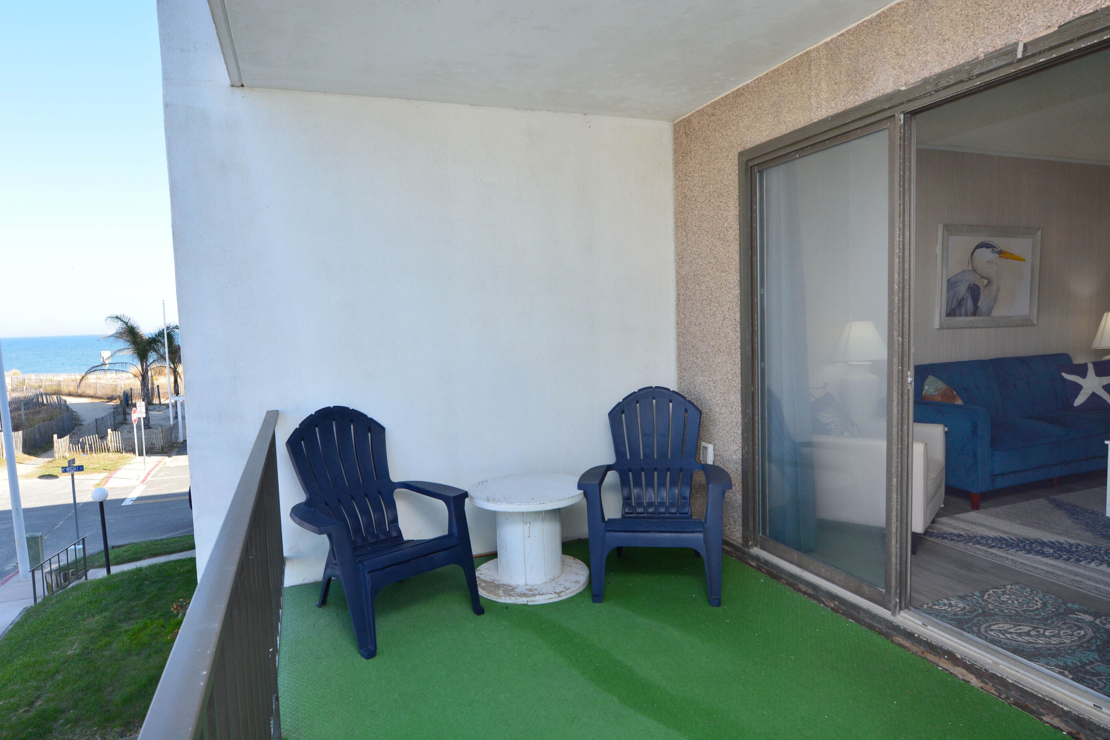 A balcony with two chairs and a small table, overlooking a street and a body of water.