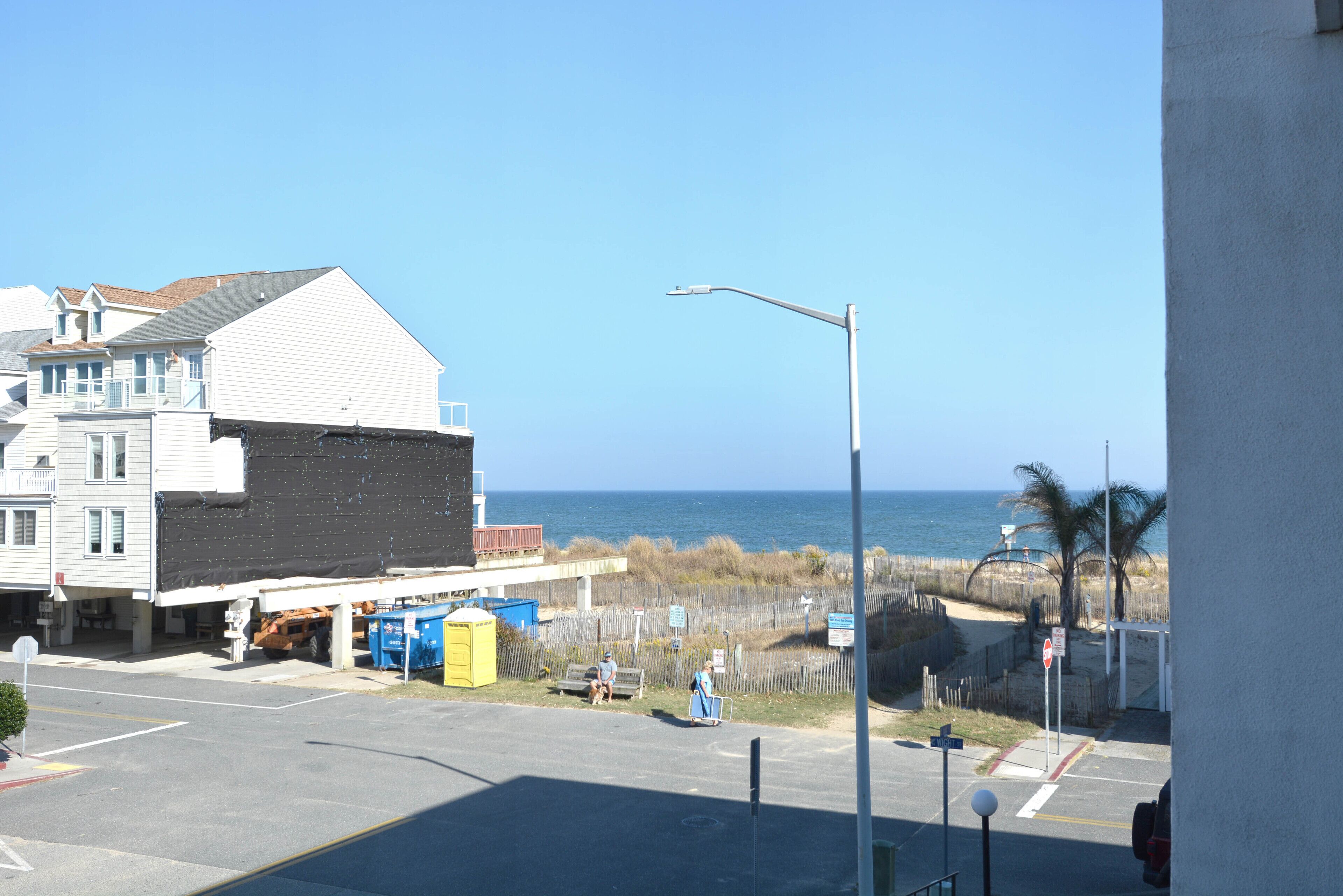 A coastal view with a building, a street, and a clear sky.