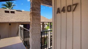 A balcony with a stone pillar, a view of a building with a palm tree, and the number A407 on a wall.