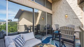 A balcony with a sofa, chairs, and a table.
