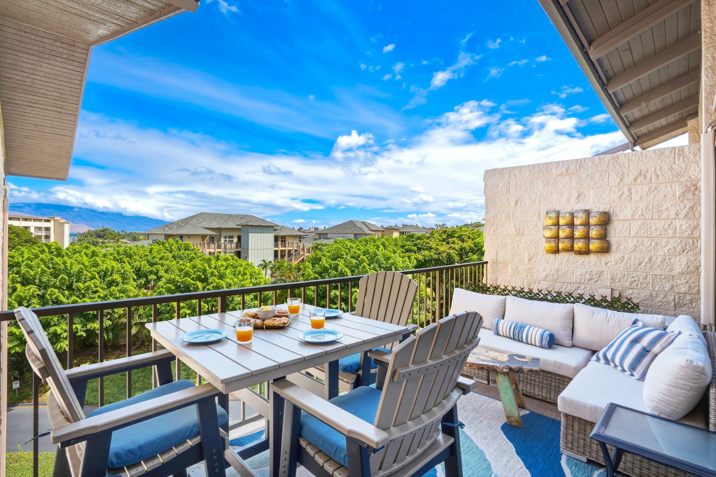 A balcony with a table set for breakfast, a sofa, and a view of a lush green landscape.