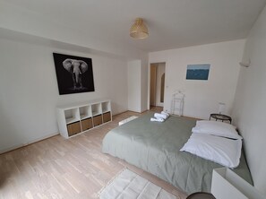 A bedroom with a bed, a white console table, a hanging light fixture, and a framed picture on the wall.