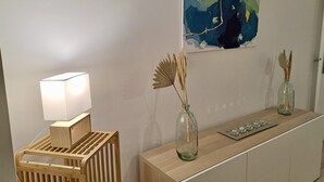 Une chambre moderne avec une console en bois, une lampe et deux vases en verre contenant des plantes séchées.