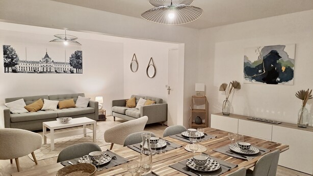Un salon moderne avec un coin repas, comprenant un ensemble de canapés, une table basse et une table à manger pour six personnes.