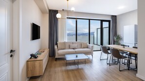 A modern living room with a sofa, coffee table, and dining area. - STEPS Batumi  Hotel & Suites (Batumi)