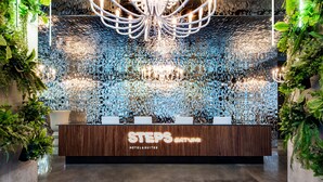 A reception desk with a wooden finish and the name "STEPS BATNMI HOTEL & SUITES" illuminated on it. - STEPS Batumi  Hotel & Suites (Batumi)