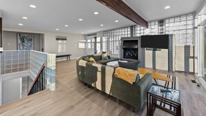 Un salon spacieux avec un grand canapé d’angle, une cheminée et un téléviseur fixé au mur.