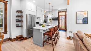 A modern kitchen with white cabinets, stainless steel appliances, and wooden bar stools. - Historic Whittier Neighborhood - Near City Park & Golf - Fenced Yard (Denver)