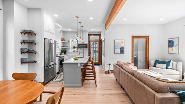 A modern kitchen with white cabinets, stainless steel appliances, and a wooden dining table. - Historic Whittier Neighborhood - Near City Park & Golf - Fenced Yard (Denver)