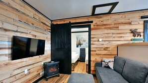 A cozy cabin interior with a TV mounted on the wall, a fireplace, a sofa, and a wooden wall with a moose decoration. - Moose Ridge at The Spot on Buskey Bay of the Pike Chain of Lakes in Iron River, WI (Iron River)
