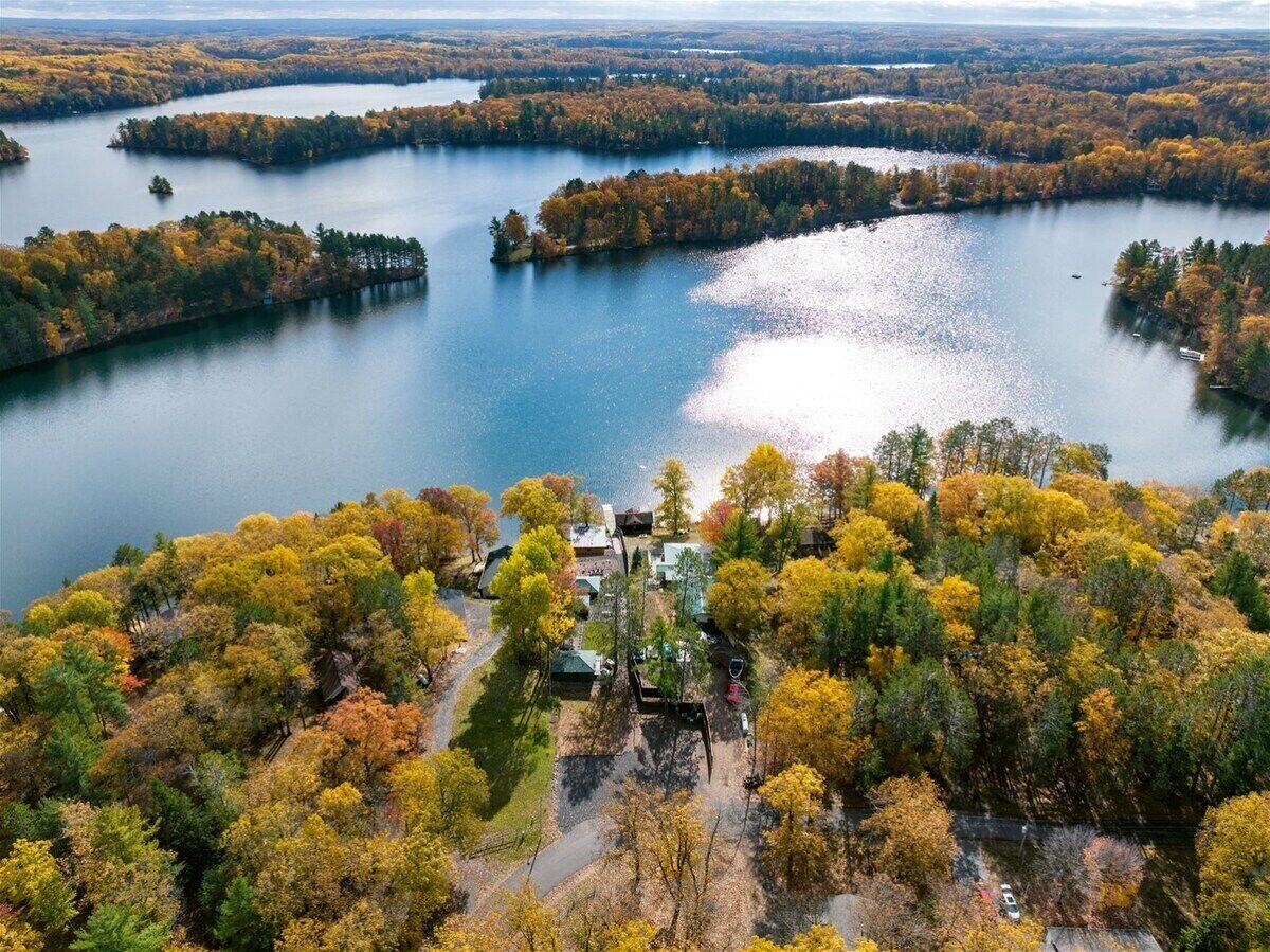 Aerial view of Moose Ridge at The Spot, featuring autumn-colored forests surrounding a calm lake under a bright sky.