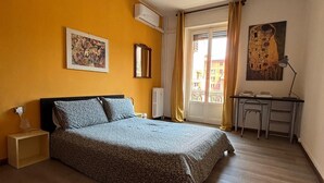 Une chambre à coucher avec un lit, un bureau, une chaise et une fenêtre avec des rideaux.